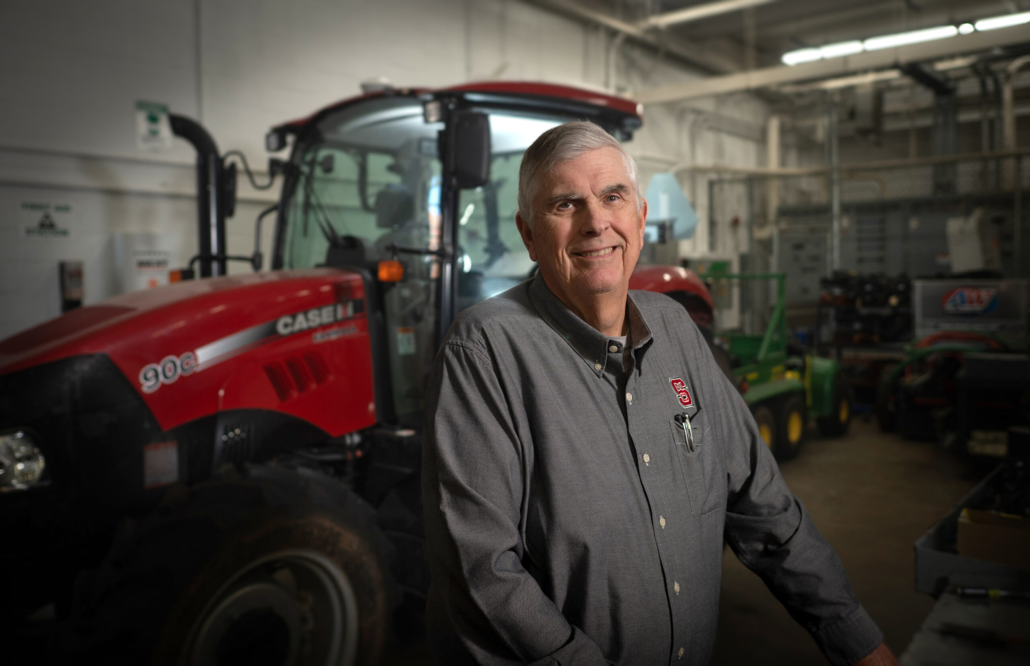 Man standing in an indoor shop in front of a tractor .