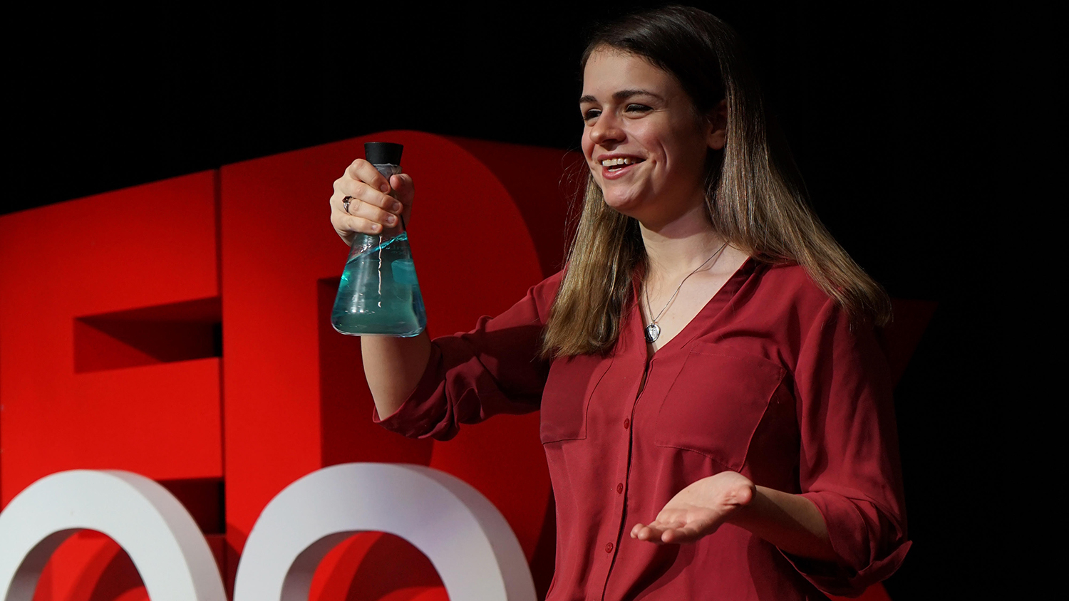 Women holding a beaker of blue water