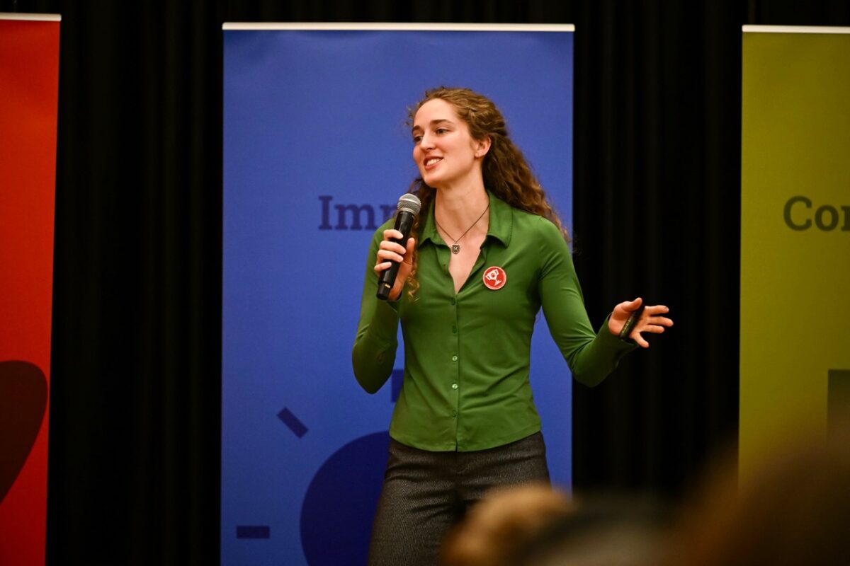 A woman speaks into a microphone on a stage.