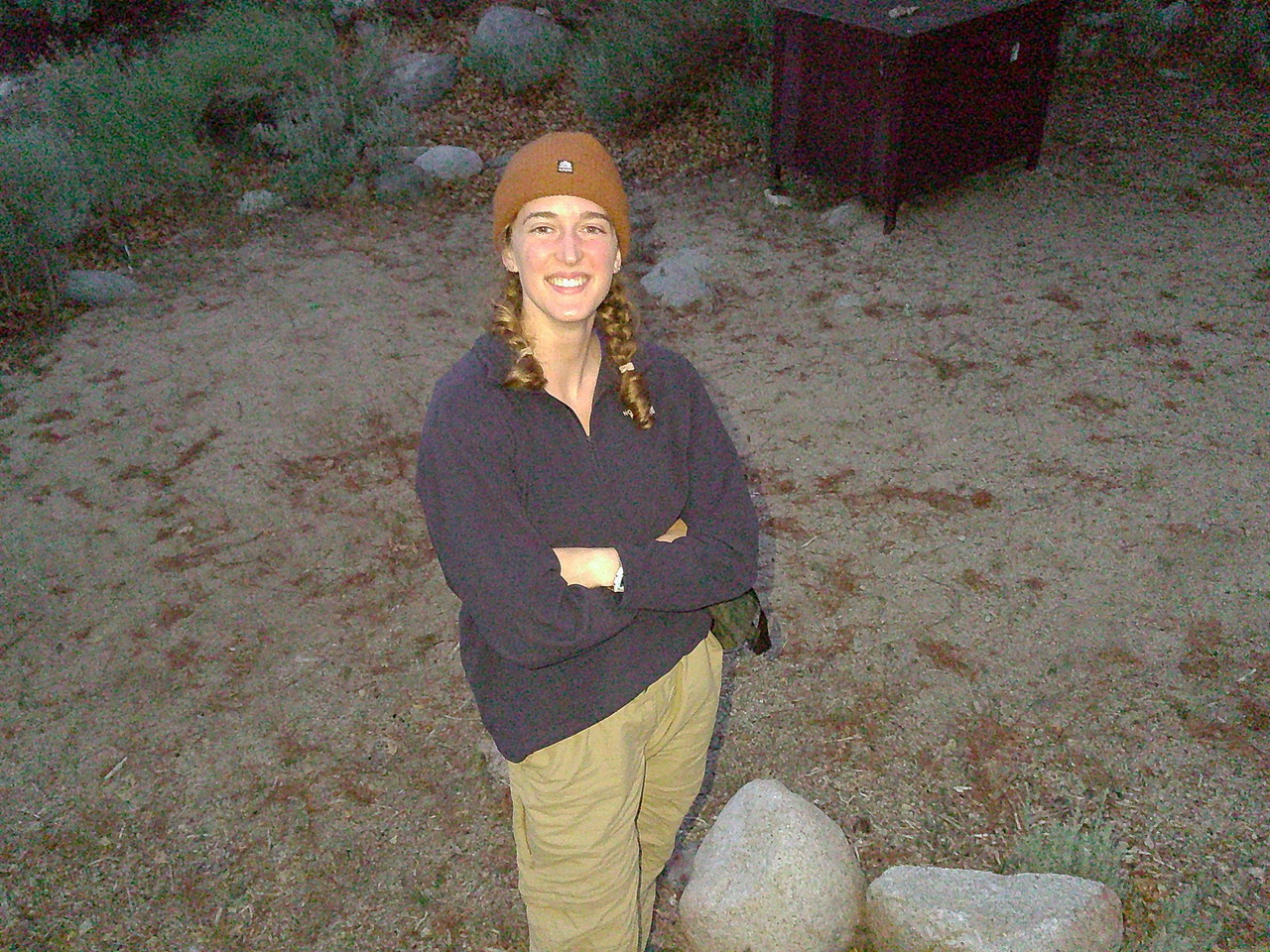 A woman poses outside wearing a beanie.