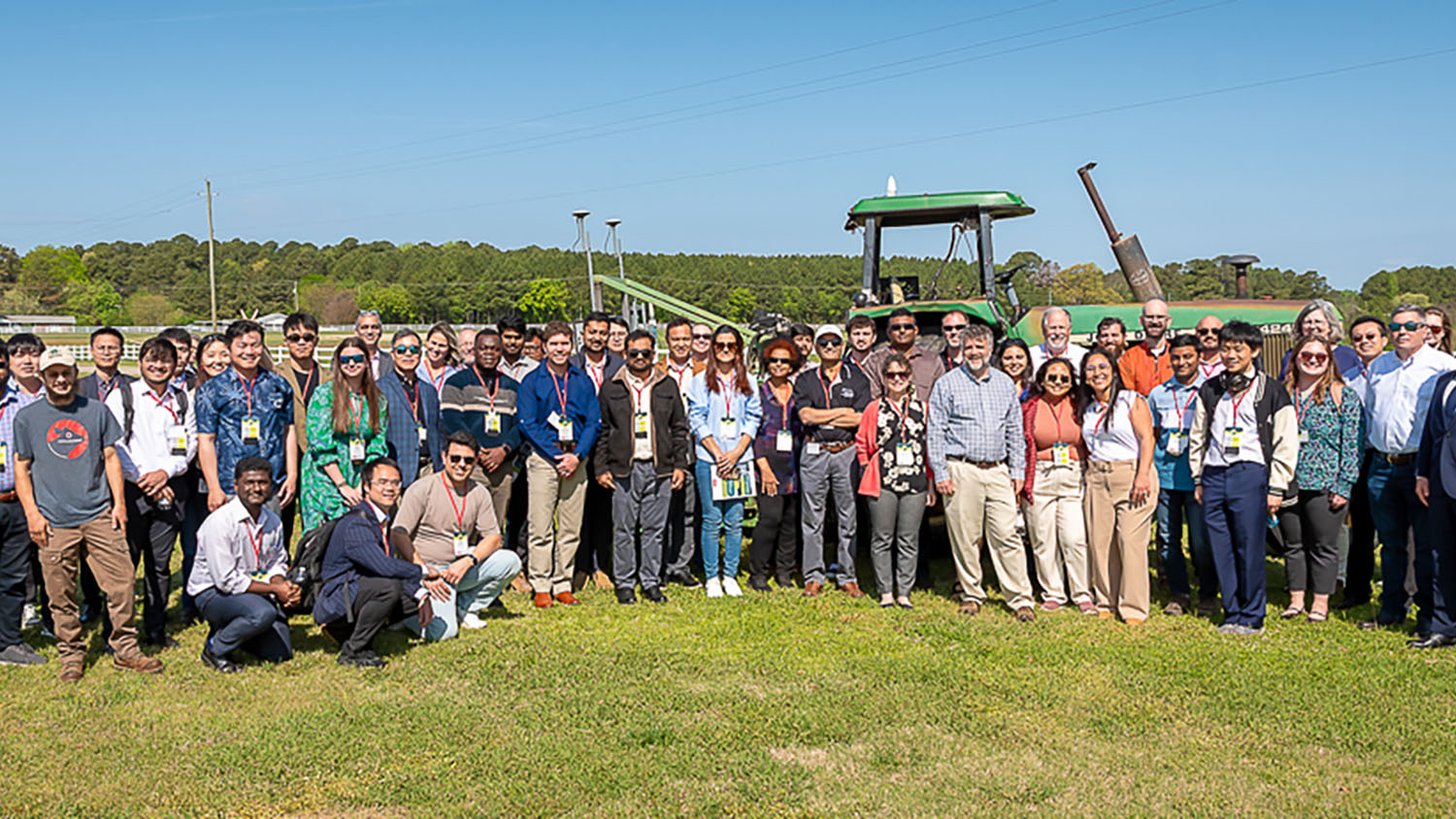 A group of people posing in front of a tractor outside.