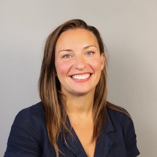 A woman smiling while wearing a navy blue shirt.