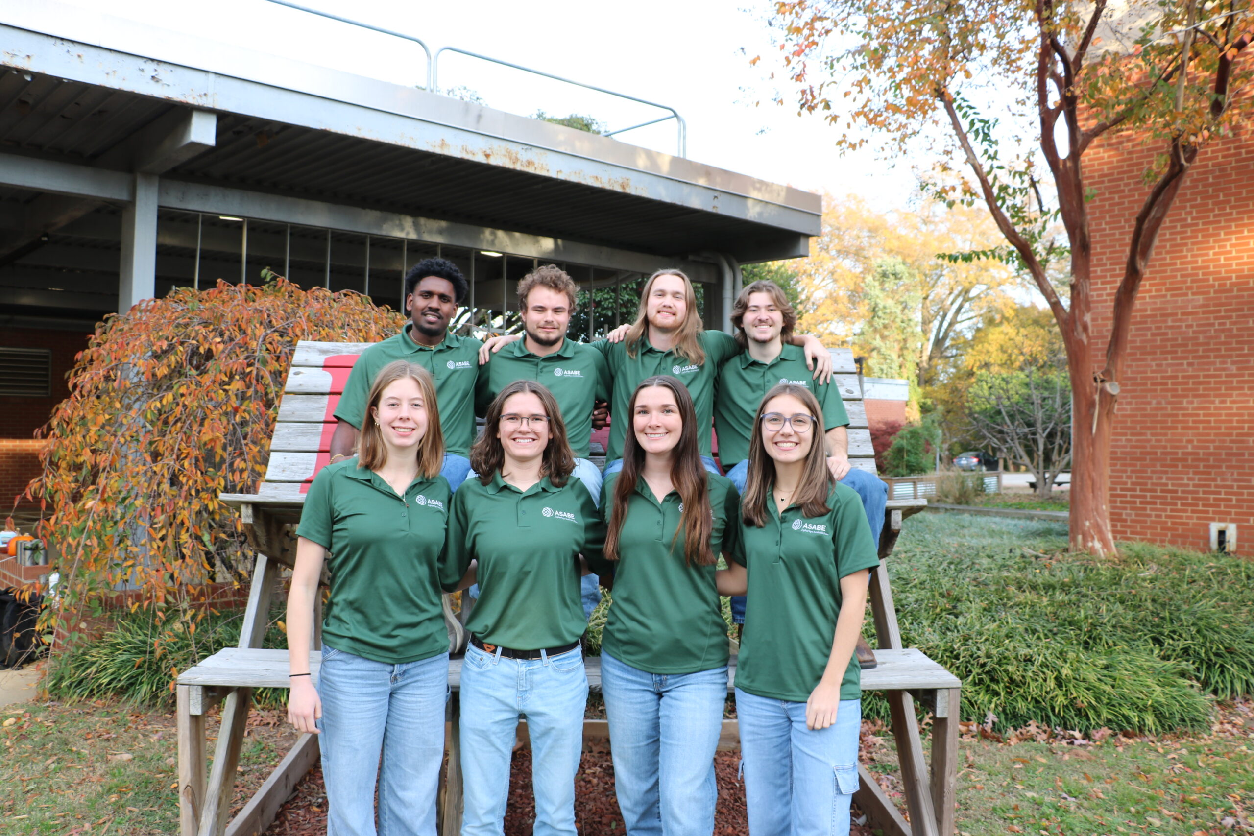 Students pose on a large bench outside 