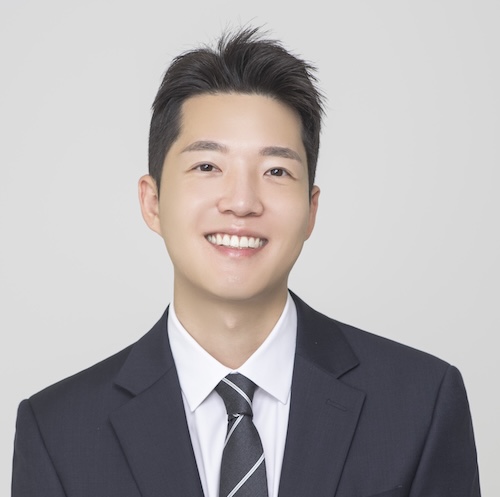 A man smiling in a suit and tie